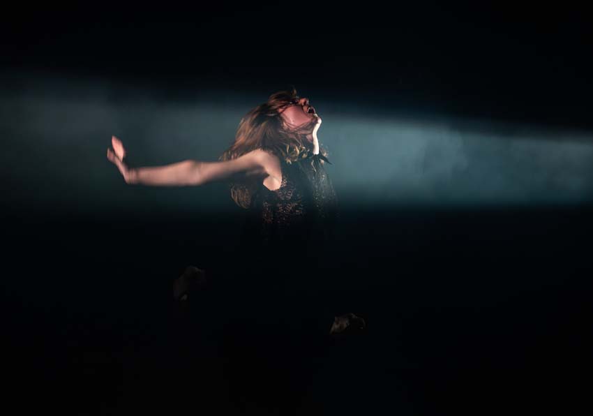 A woman illuminated by a spotlight acting